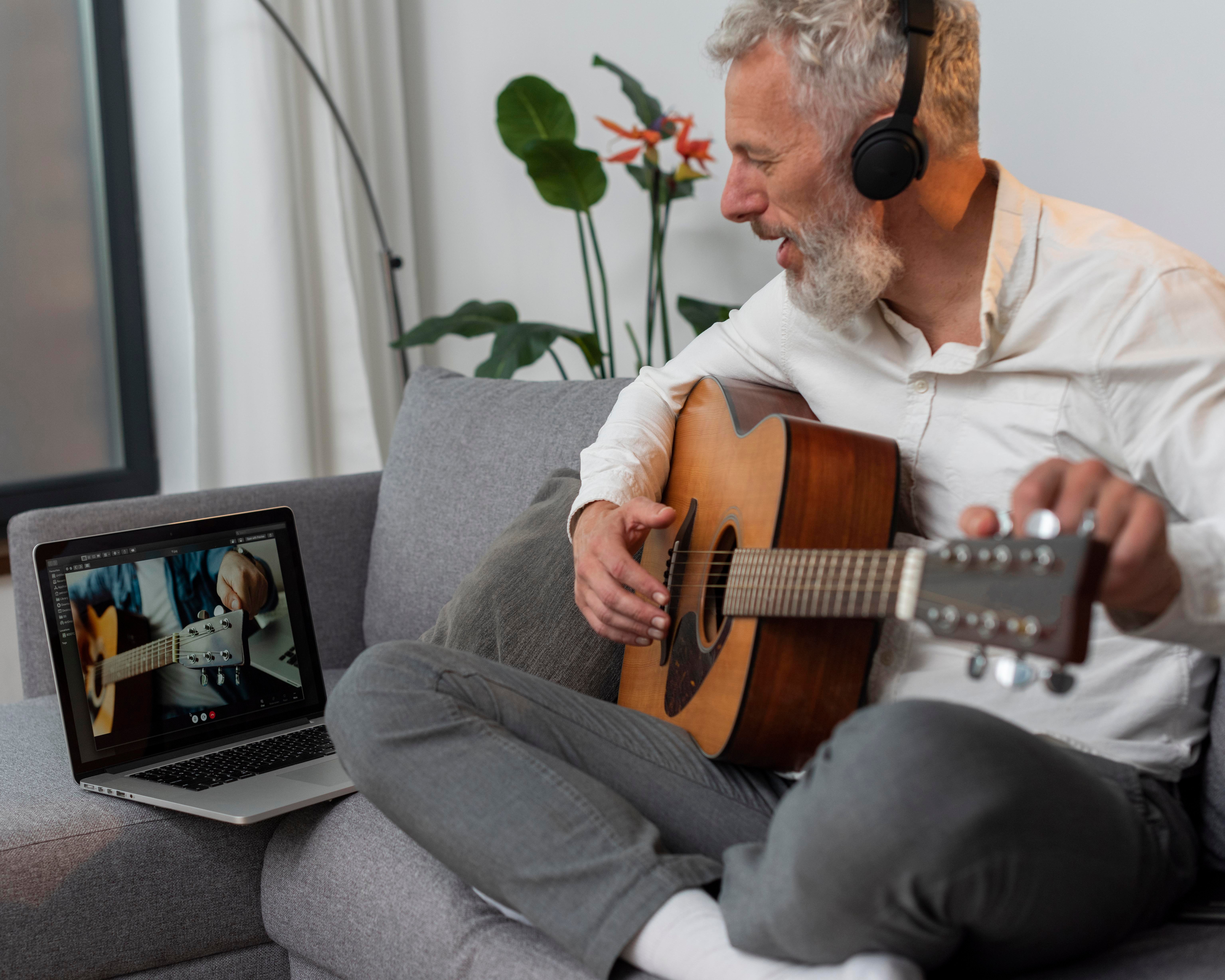 senior-man-home-couch-using-laptop-study-guitar-lessons (1)